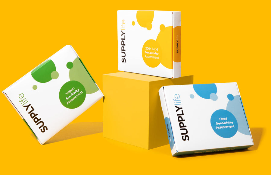 Three food sensitivity assessment kits displayed against a vibrant yellow background. The kits are in white boxes with colorful designs: green for 'Sensitivity Assessment', yellow for '200+ Food Sensitivity Assessment', and blue for 'Food Sensitivity Assessment